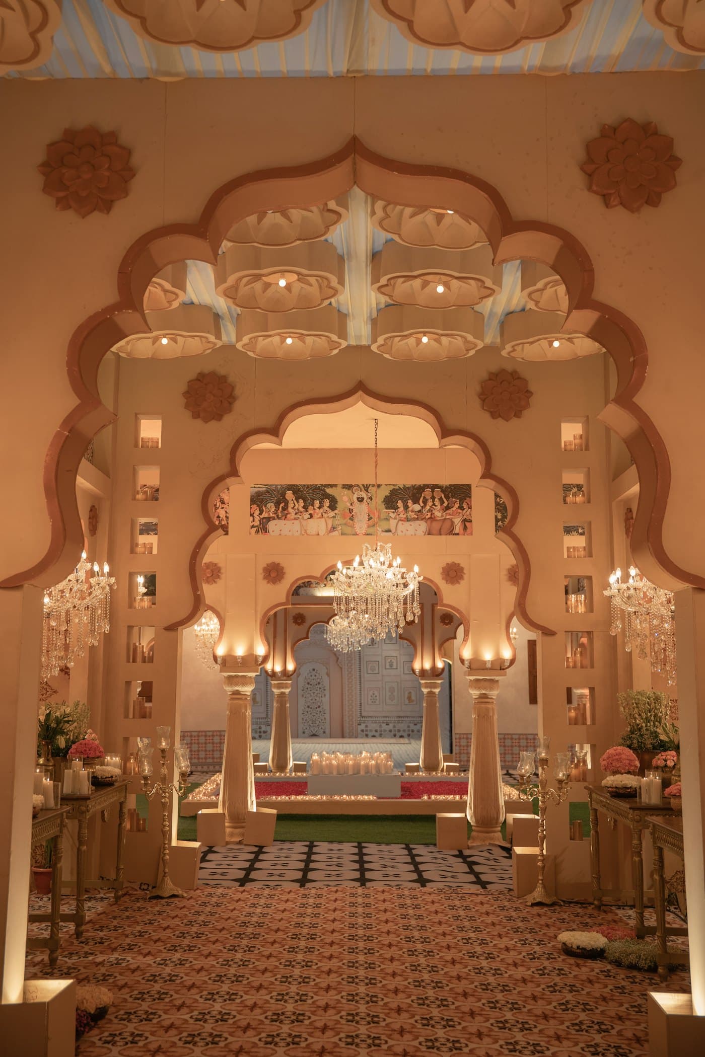 An ornate arched entrance lit with chandeliers and lined with seating