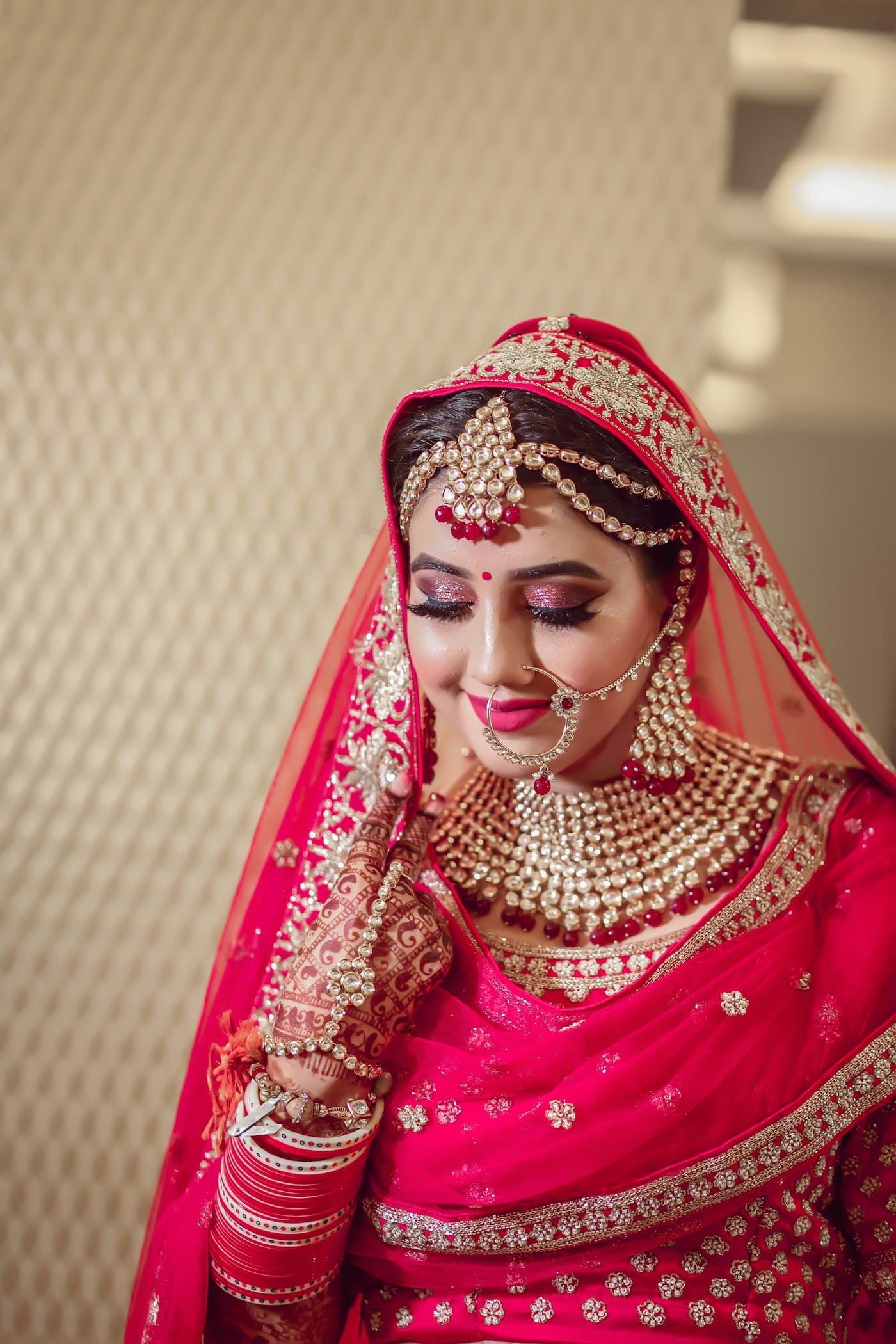 A bride in red bridal attire with gold jewellery and henna
