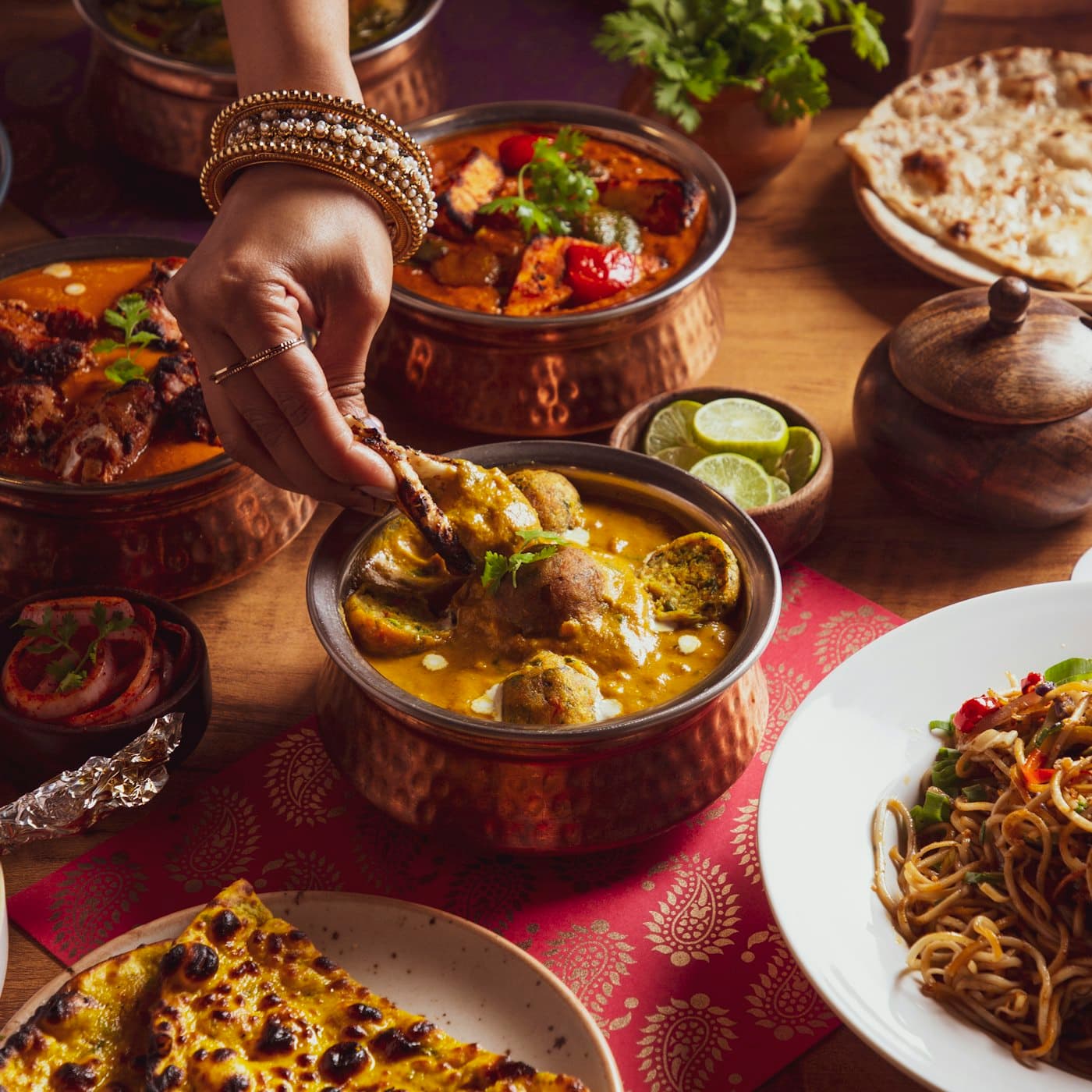 A table filled with Indian dishes, curries, breads and sweets