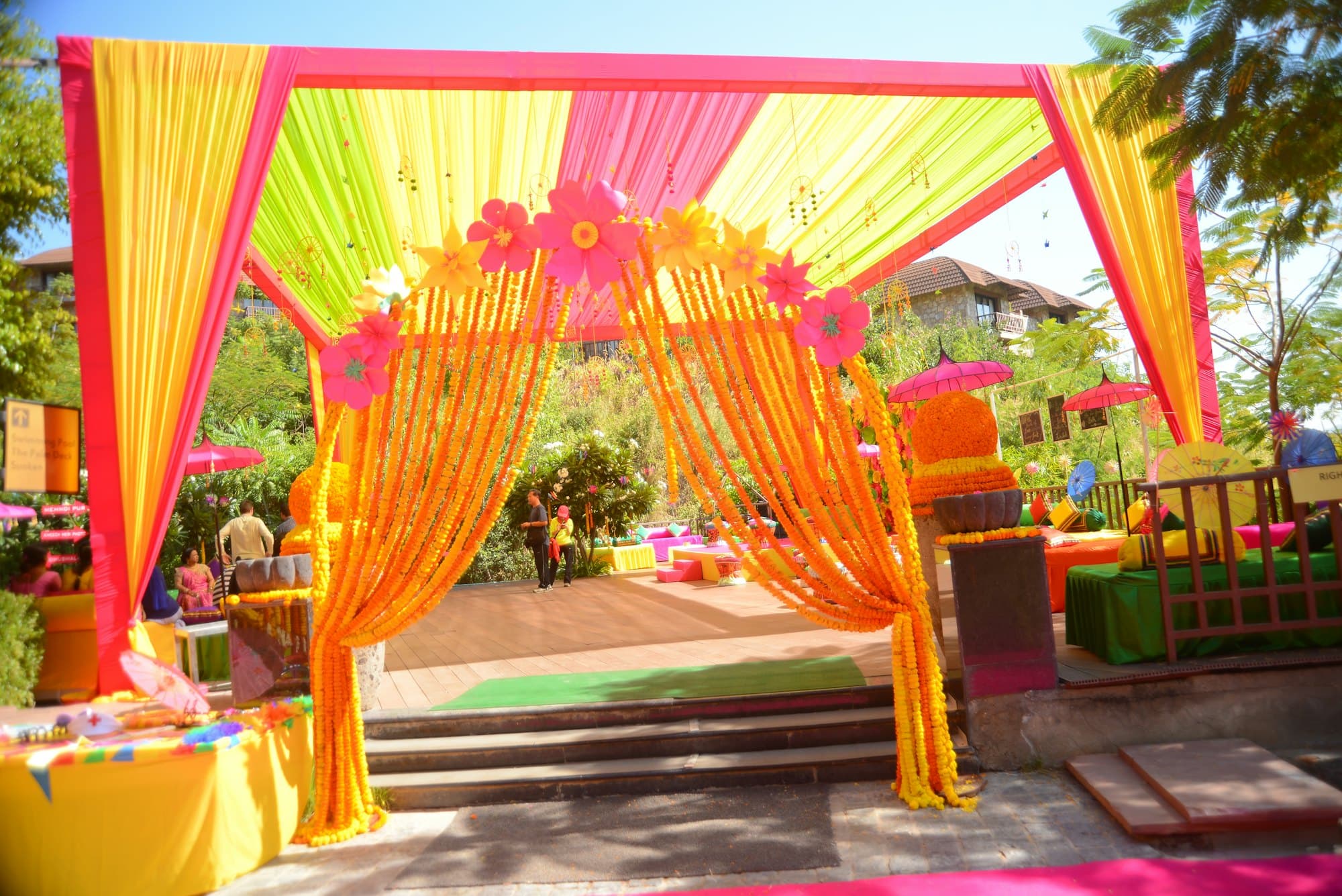 A bright entrance gate draped with strings of marigold flowers and yellow and pink fabric