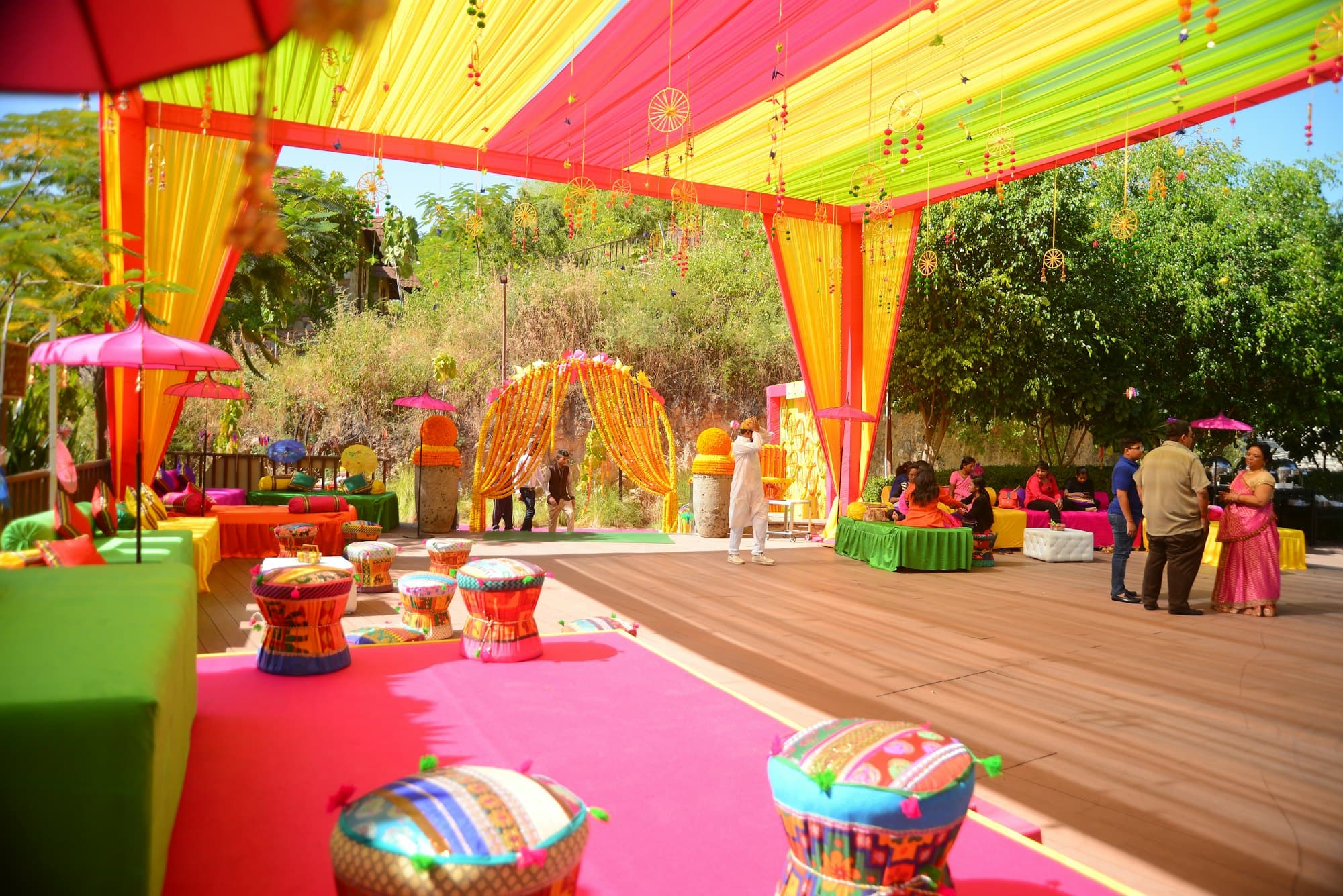 A colourful outdoor function with bright canopies, floor seating and marigold décor