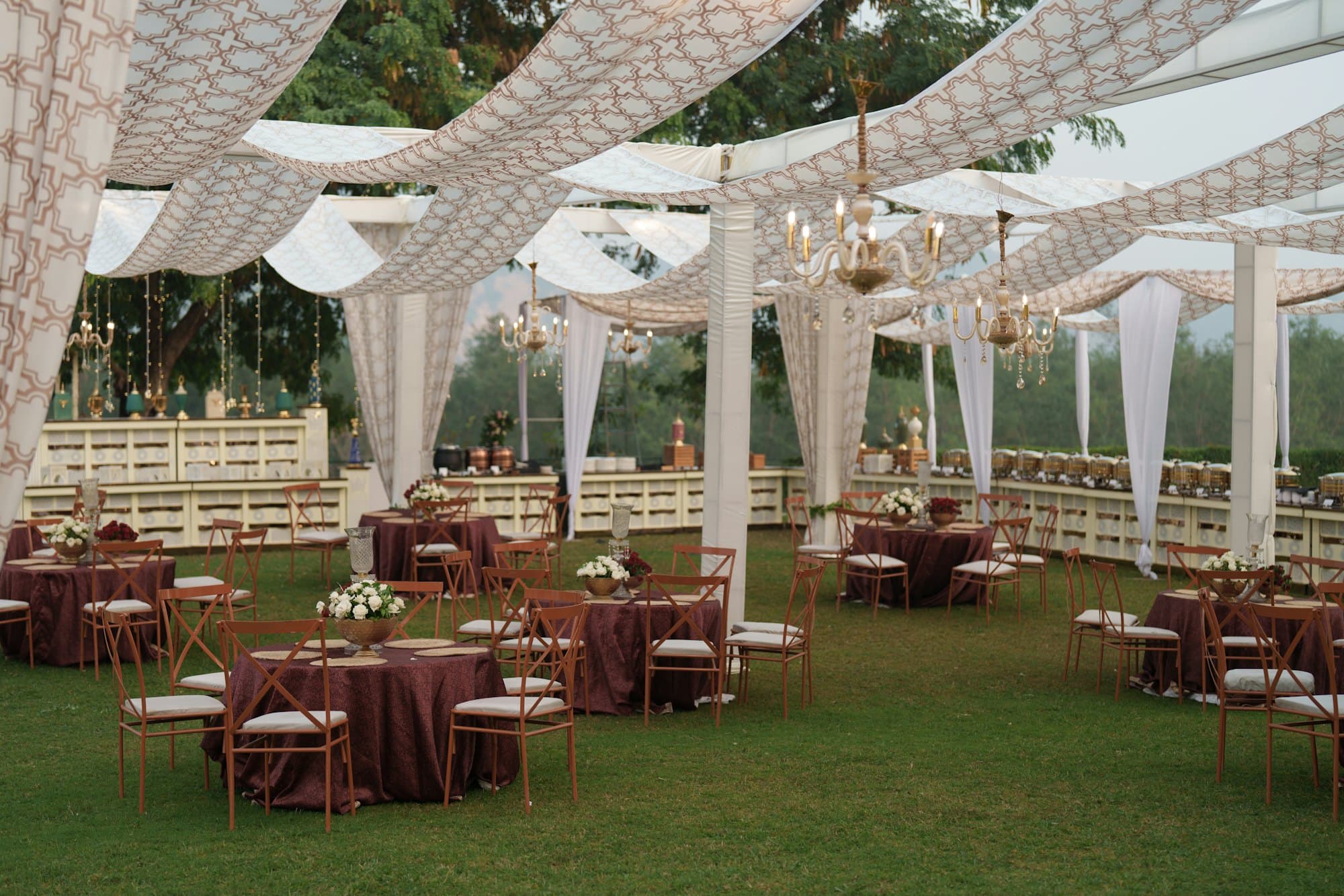 An elegant outdoor reception with draped canopy and set tables