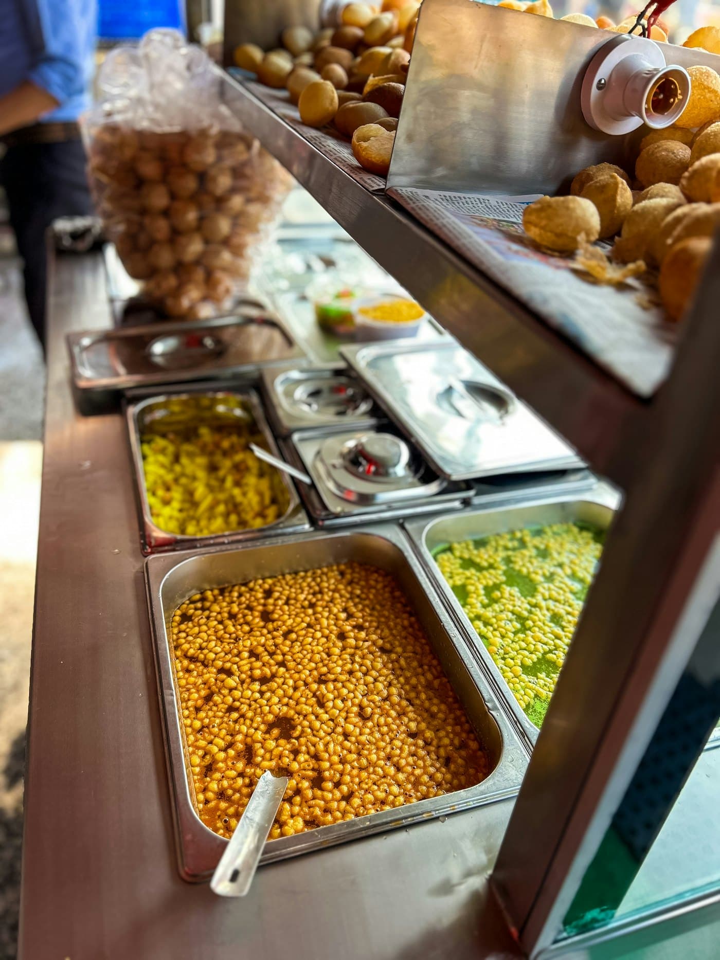 A long buffet counter of Indian dishes in polished serving vessels